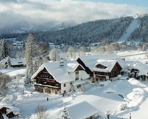 Luftaufnahme über der winterlichen Landschaft rund um den Bio-Bauernhof Simonbauer mit Apartments, Ferienhaus, Penthaus und Zimmer in Ramsau am Dachstein