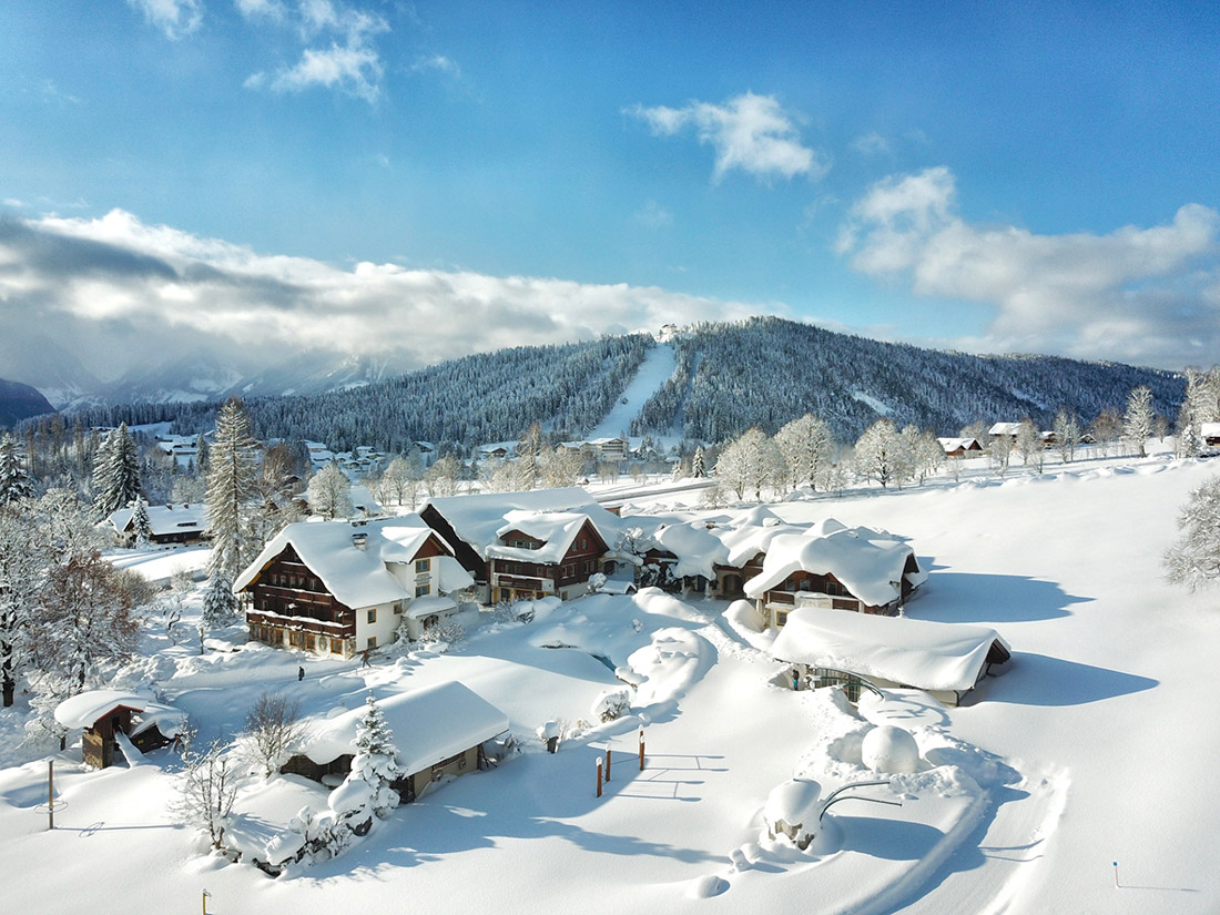 Luftaufnahme über der winterlichen Landschaft rund um den Bio-Bauernhof Simonbauer mit Apartments, Ferienhaus, Penthaus und Zimmer in Ramsau am Dachstein